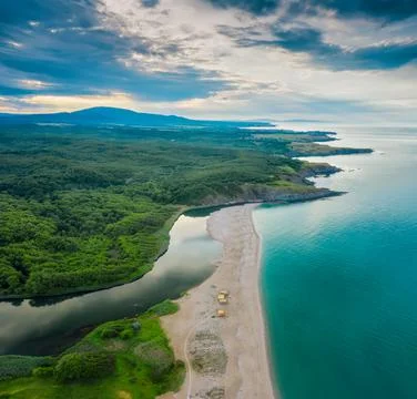 An empty wild beach, surrounded by rocks and green thick forests Stockfoto's