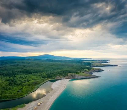 An empty wild beach, surrounded by rocks and green thick forests Stockfoto's