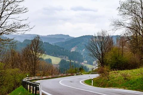Empty winding road through forests in mountains. Stock Photos