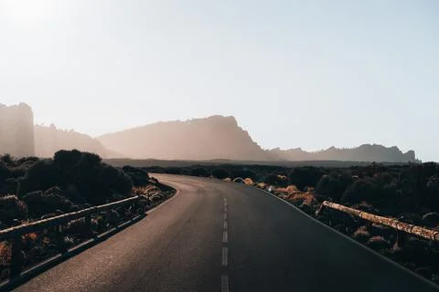 Empty winding road through a mountainous landscape during golden hour Foto stock