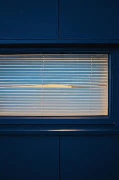 Empty window with blinds and peephole at night Foto stock