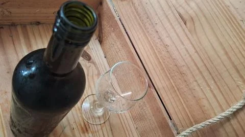 Empty wine bottle and clear glass resting on rustic wooden planks Stock Photos