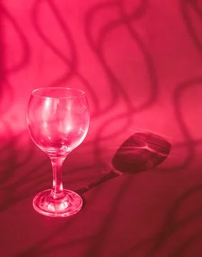 An empty wine glass on a red background with sunshine shadow effect Foto stock