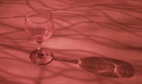 An empty wine glass on a red background with sunshine shadow effect Foto stock