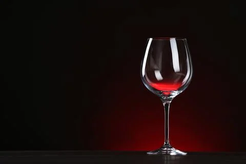Empty wine glass on table against dark background, space for text Stock Photos
