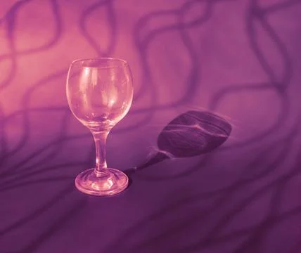 An empty wine glass on a violet background with sunshine shadow effect Stock Photos