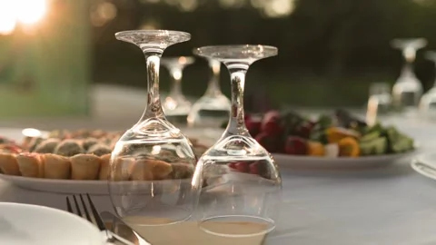 Empty wine glasses on banquet served table in open air in rays of setting sun Stock Footage 279382039