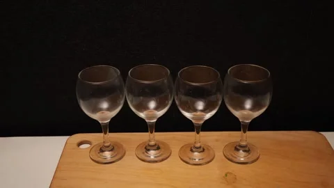 Empty Wine Glasses Lined Up on a Wooden Board Against a Dark Background Stock Footage 339181732