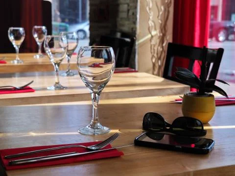 Empty wine glasses on restaurant table with a smartphone and sunglasses besid Stock Photos