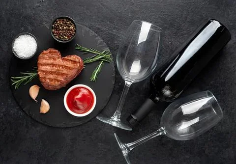 Empty wine glasses with steak and condiments on black table Stock Photos