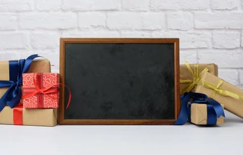 Empty wood frame and stack of various gift boxes on white brick background 스톡 사진