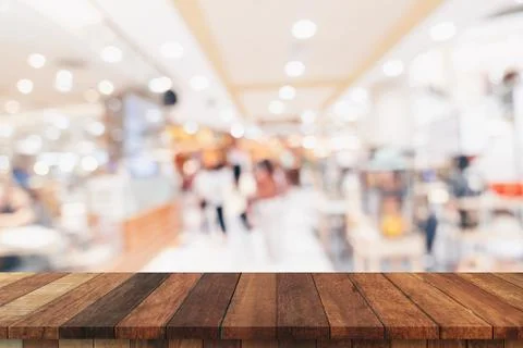 Empty wood table and blurred light table in shopping mall with bokeh backgrou Stock Photos