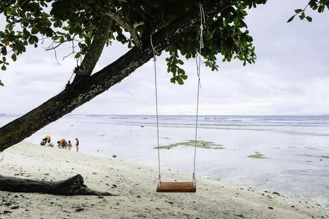 An empty wooden beach swing on the sandy shoreline of Krui Beach in Lampung Stock Photos