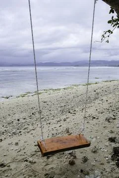 An empty wooden beach swing on the sandy shoreline of Krui Beach in Lampung Stock Photos