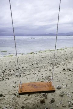An empty wooden beach swing on the sandy shoreline of Krui Beach in Lampung Stock Photos