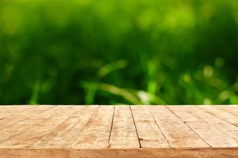 Empty wooden deck table with foliage bokeh background. Ready for product disp Stock Photos