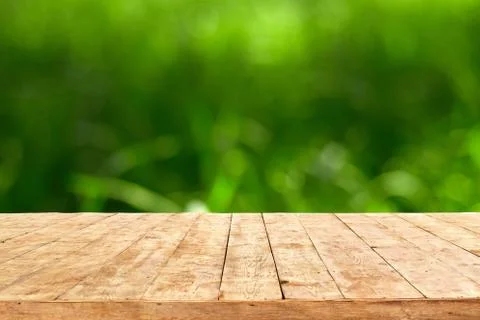 Empty wooden deck table with foliage bokeh background. Ready for product disp Stock Photos