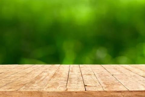 Empty wooden deck table with foliage bokeh background. Ready for product disp Stock Photos