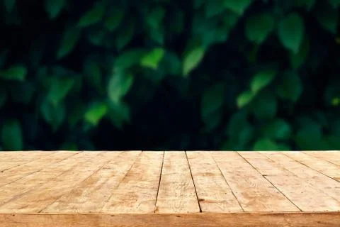 Empty wooden deck table with foliage bokeh background. Ready for product disp Stock Photos