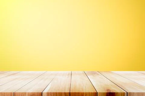 Empty wooden deck table over yellow wallpaper background. Stock Photos