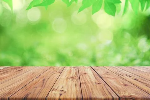 Empty wooden deck table top on green blurred abstract background from foliage Stock Photos