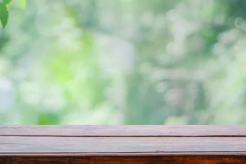 Empty wooden deck table top on green blurred abstract background from foliage Stock Photos