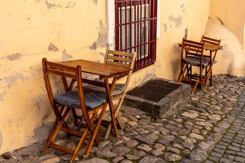 Empty Wooden Dining Setup on Cozy Cobblestone Alley Terrace Stock Photos