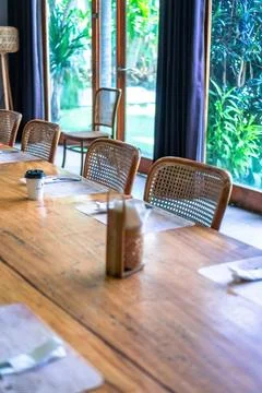 Empty wooden dining table with rattan chairs in a bright restaurant setting Stock Photos