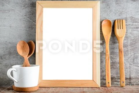 Empty wooden frame and kitchen utensils on a wooden table Stock Photos