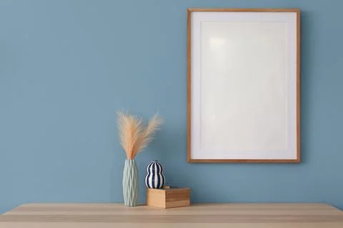 Empty wooden frame on a blue wall with decorative vases and pampas grass on a Stock Photos