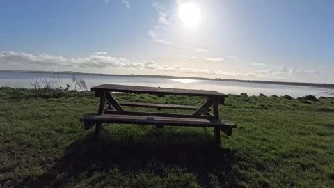 Empty wooden park picnic table looking out across ocean beach coast in morning Stock Footage 333019907