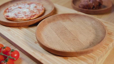 Empty Wooden Plates On Bamboo Board With Cherry Tomatoes And Pizza In Background Stock Footage 324838079
