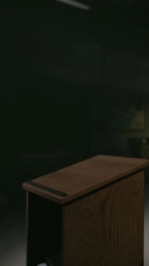 Empty wooden podium in a dimly lit room with a chair and wall Stock Footage 336249815