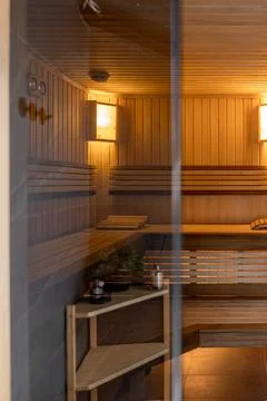 Empty wooden sauna interior behind glass door. Warm wellness room with benche Stock Photos