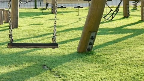 Empty Wooden Swing Hangs Over Bright Green Artificial Grass At A Playground Stock Footage 335785118
