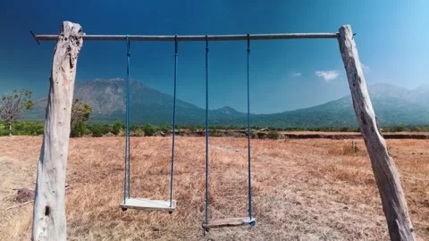Empty Wooden Swing Set in Arid Field Overlooking Volcanic Mountains Landscape Video stock 343327741