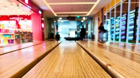 Empty wooden table with blurred background of shops in shopping center. Cop.. Stock Photos
