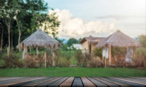 Empty wooden table, blurred background of the garden, and a small house Stock Photos