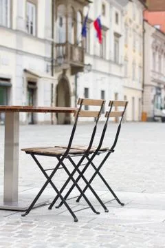 Empty wooden table with chairs in front of cafe in old city center. Stock Photos