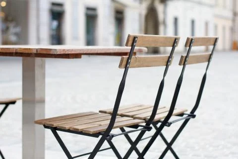 Empty wooden table with chairs in front of cafe in old city center. Stock Photos