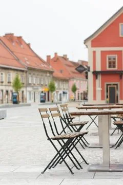 Empty wooden table with chairs in front of cafe in old city center. Stock Photos