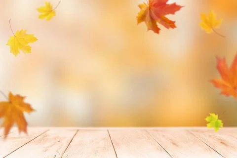 Empty wooden table with falling maple leaves for an autumn product display Stock Photos