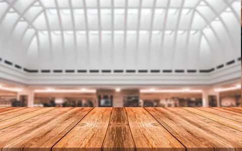 Empty wooden table in front of abstract blurred background of shopping mall Stock Photos