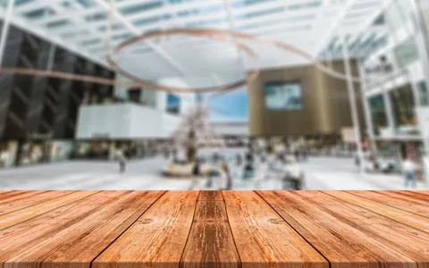 Empty wooden table in front of abstract blurred background of shopping mall Stock Photos