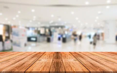 Empty wooden table in front of abstract blurred background of shopping mall Stock Photos