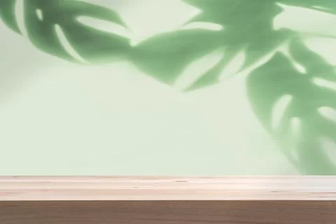 Empty wooden table with shadow of tropical green leave on color background 写真素材
