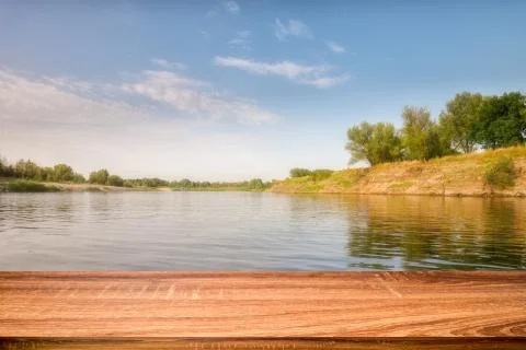 Empty wooden table with summer background of riverside in the daytime for dis Stock Photos