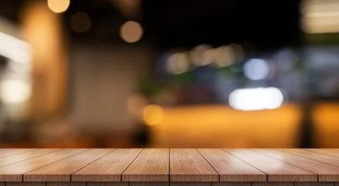 Empty wooden table top with lights bokeh on blur restaurant background. Photos