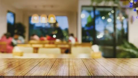 Empty wooden table top with lights bokeh on blur restaurant background. Photos