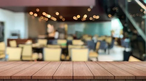 Empty wooden table top with lights bokeh on blur restaurant background. Photos